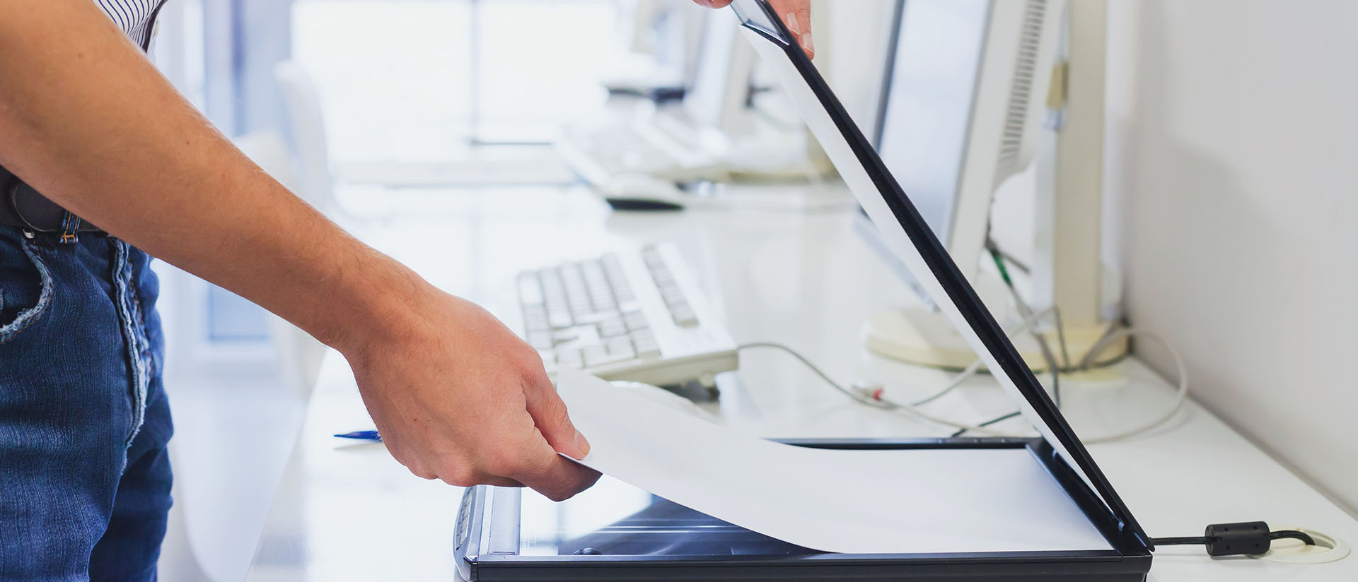 Eine Person, die ein Blatt Papier auf den Scanner legt