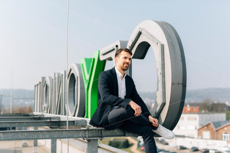 Mann der vor dem Logo der Ceyoniq Technology GmbH sitzt