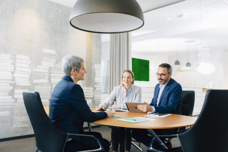 Drei Geschäftspartner die zusammen an einem Tisch im Besprechungsraum der Ceyoniq Technology GmbH sitzen